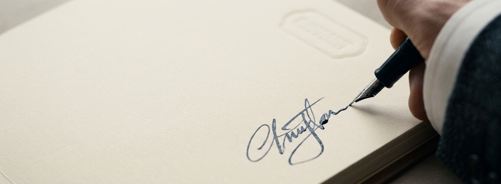 A dark fountain pen completing a signature on a thick dossier cover.